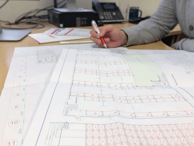 person working at desk with printed autocad drawing