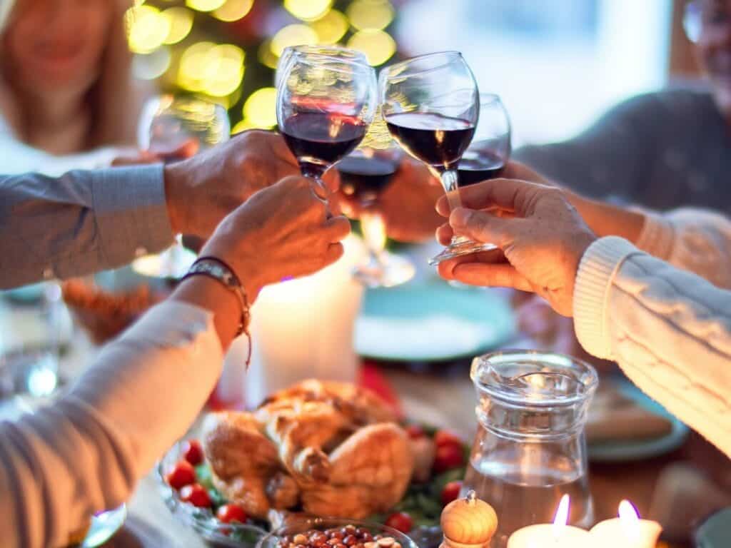 multiple people toasting with glasses of red wine