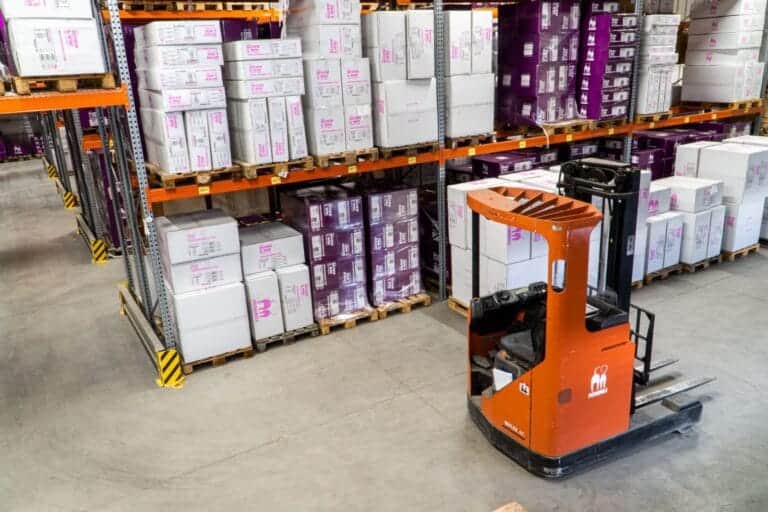fork lift truck in warehouse aisle filled with pallets